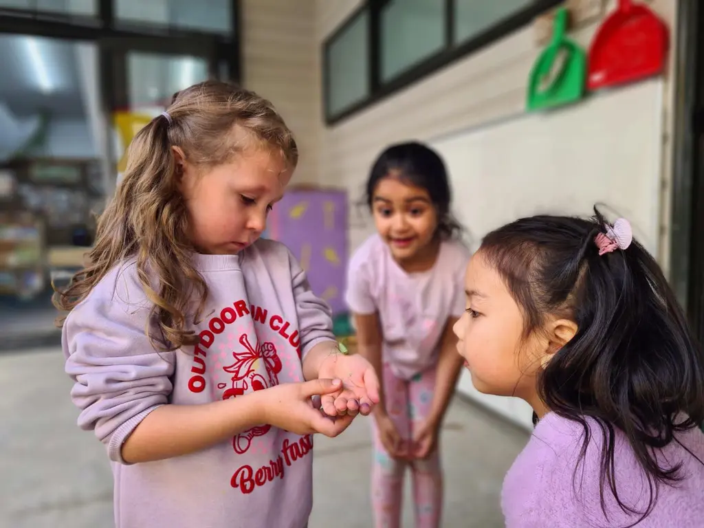 Children showing gentle care while observing a praying mantis up close.