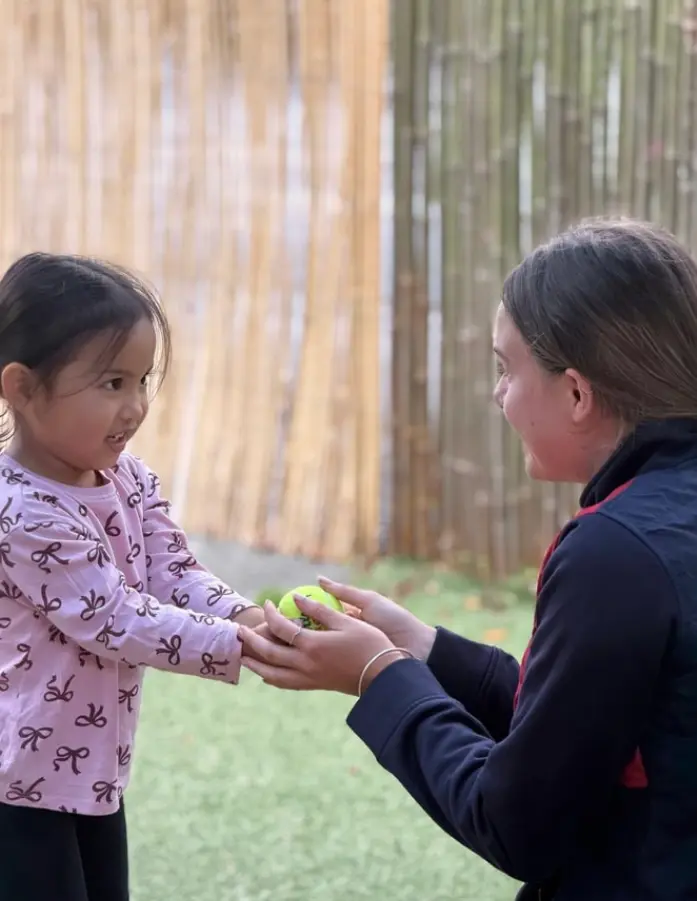 Teacher and child sharing a playful learning moment at Paramount Grove