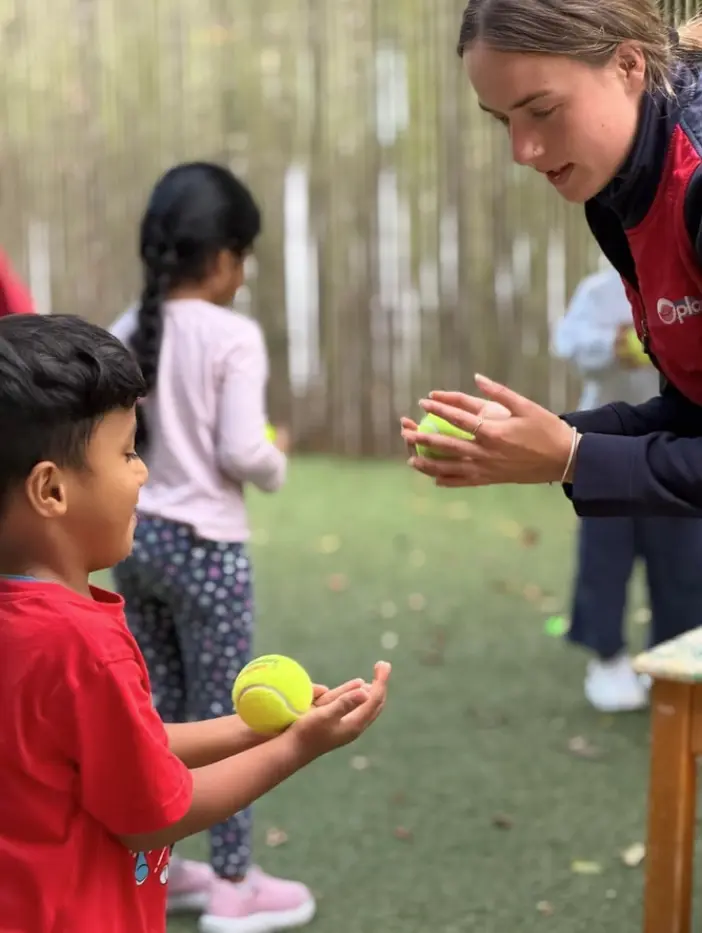 Teacher supporting a child during outdoor play at Paramount Grove