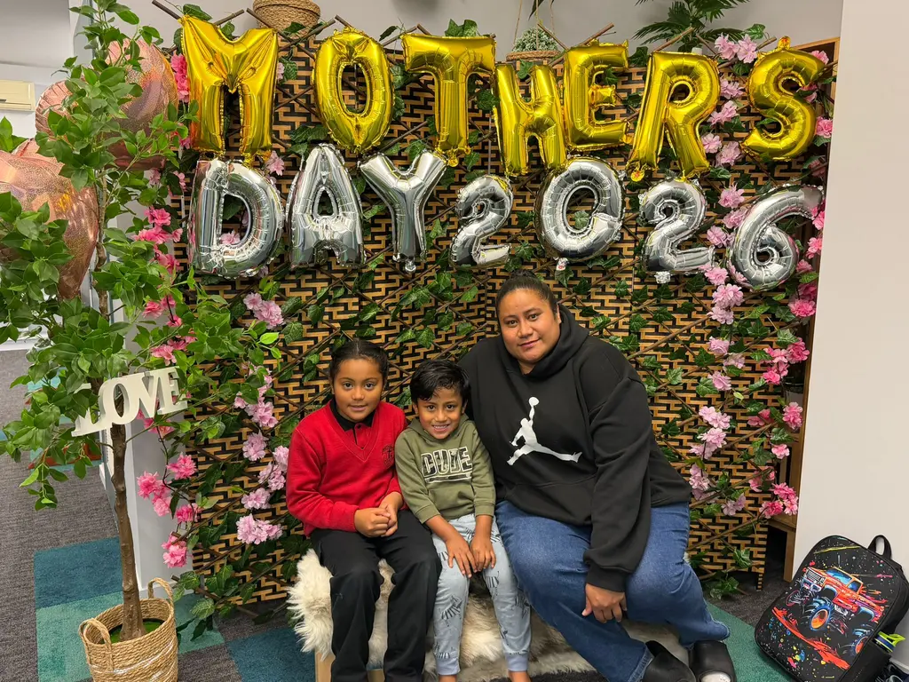 A family group sitting together in front of the Mother's Day backdrop at Paramount Grove.