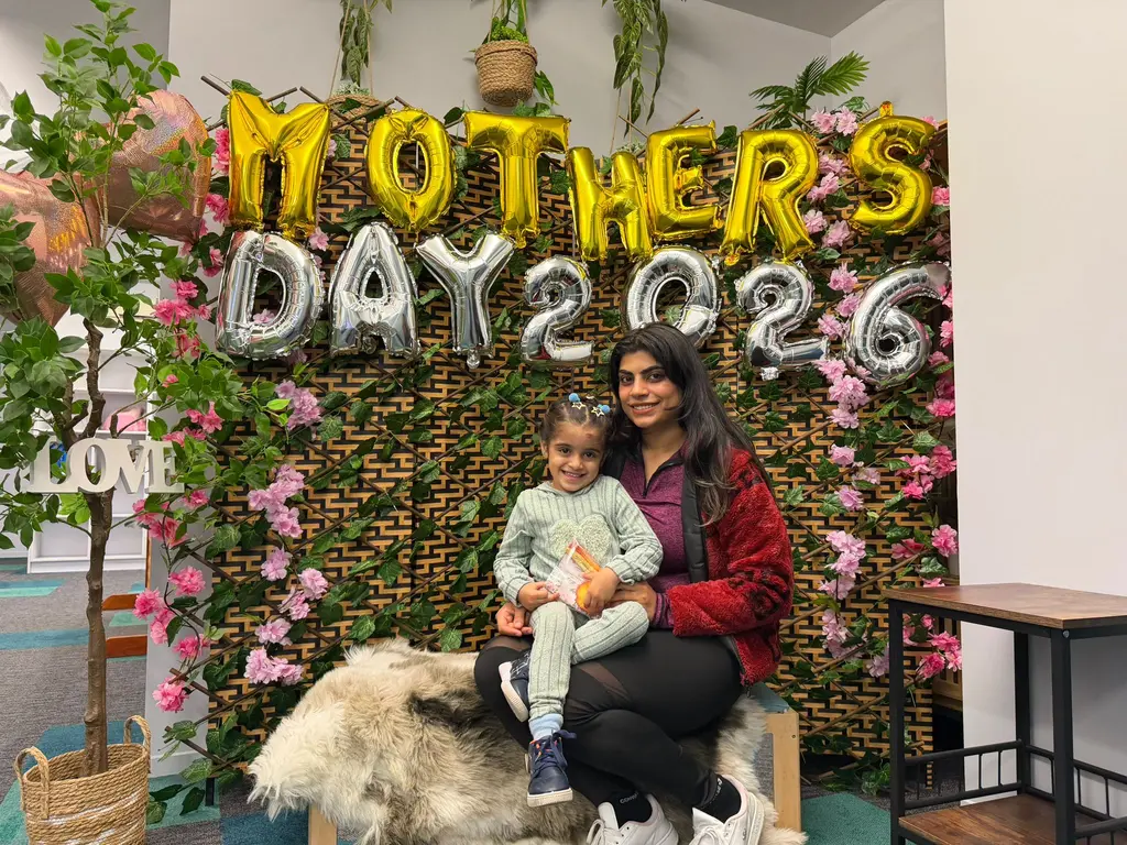 A caregiver and child seated together in front of Paramount Grove's decorated Mother's Day display.
