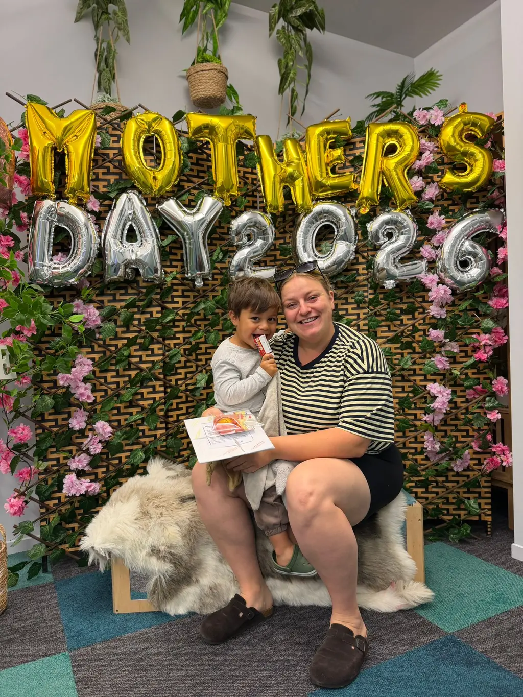 A mother and child holding a handmade card during the Mother's Day celebration at Paramount Grove.