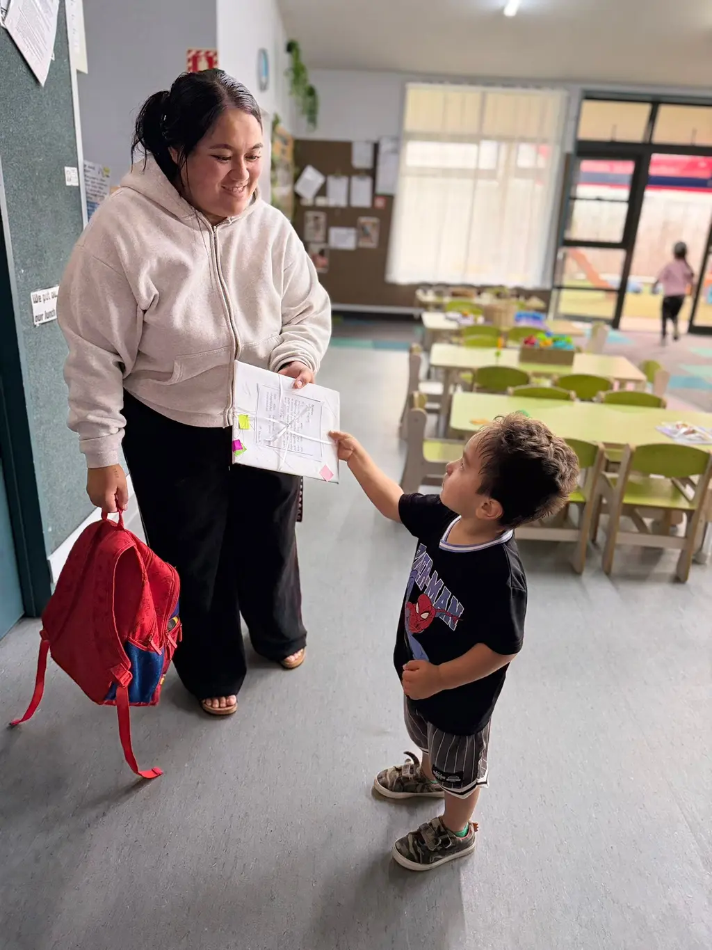 A child handing a Mother's Day card to a caregiver inside Paramount Grove.