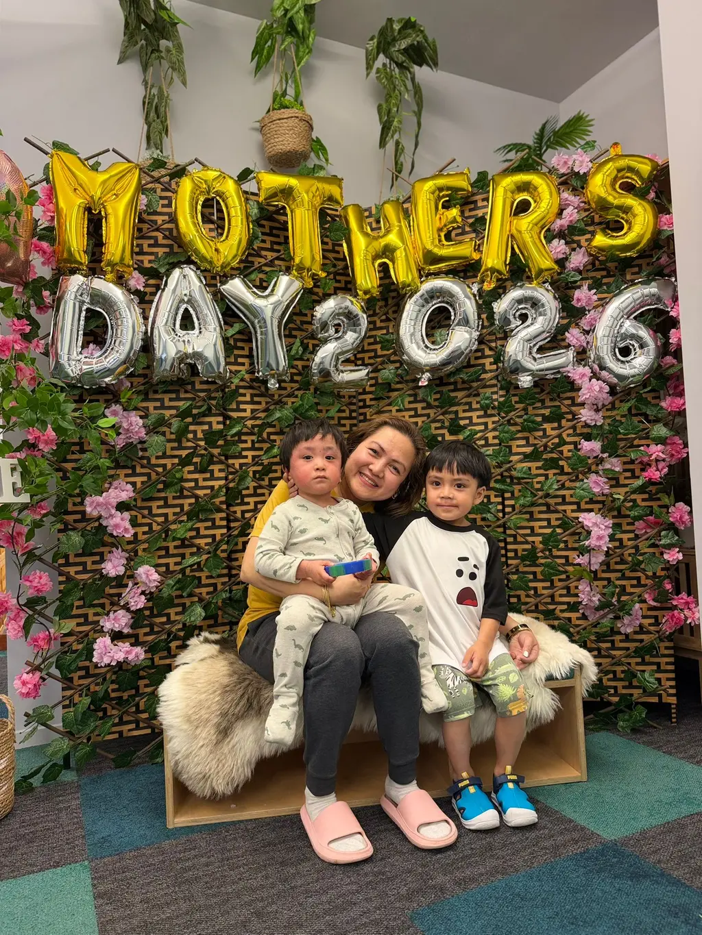A caregiver and two children smiling together during Paramount Grove's Mother's Day celebration.