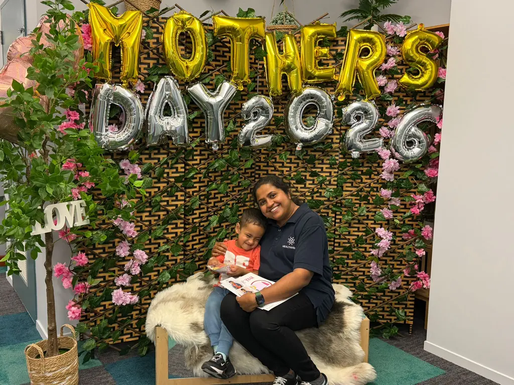 A mother and child cuddling together in front of the Mother's Day backdrop at Paramount Grove.