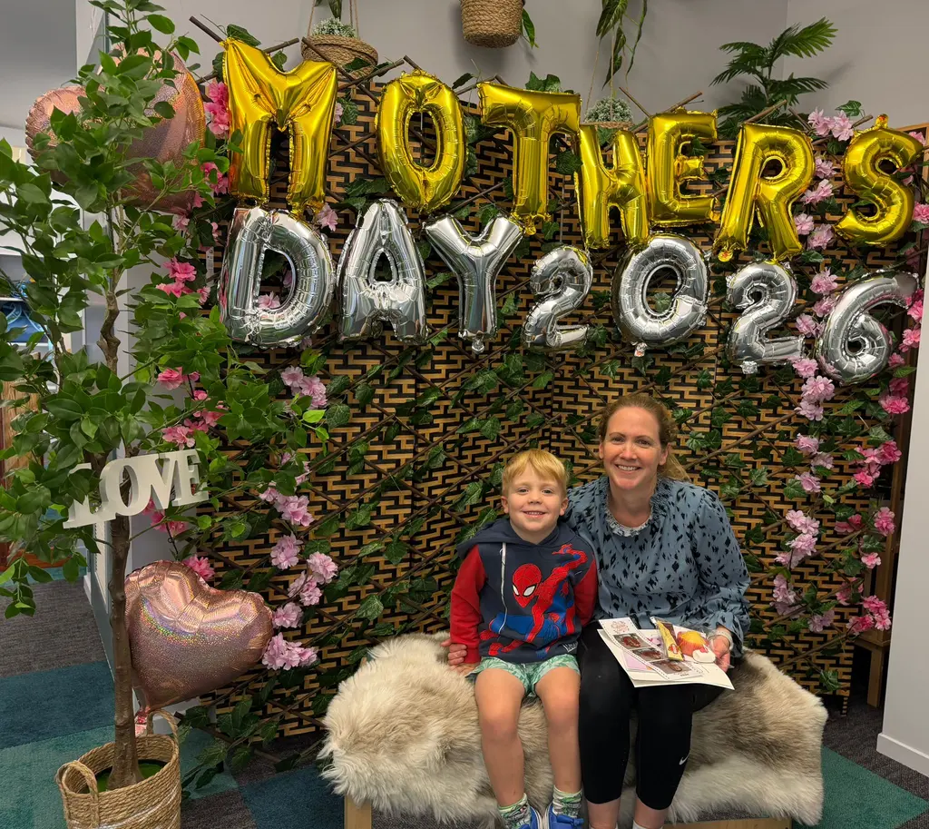 A caregiver and child sitting together beside the Mother's Day display at Paramount Grove.